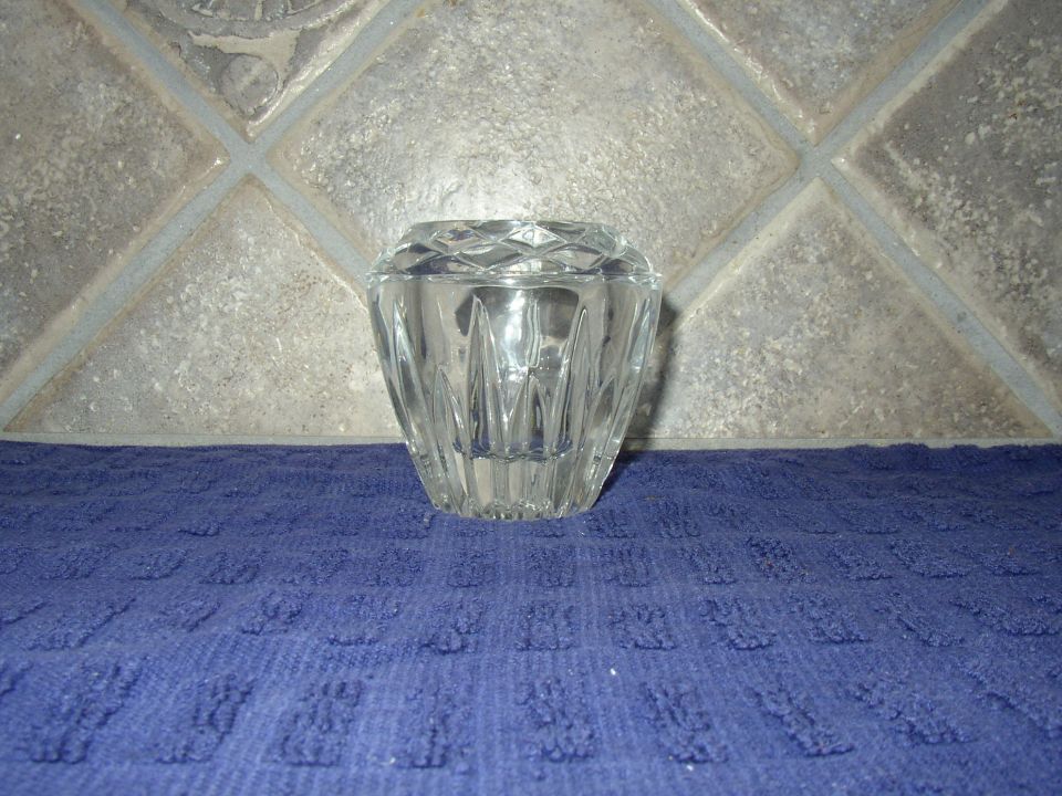 Clear faceted crystal glass dish on a blue towel near tiled wall.