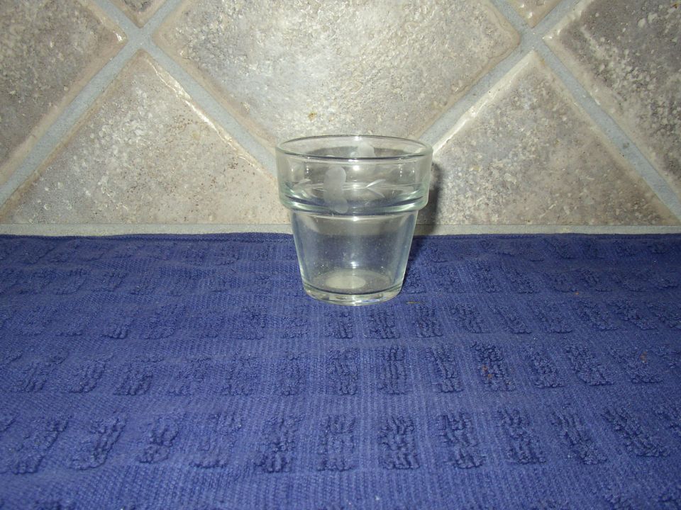 Small clear drinking glass on a blue cloth against a tan diamond-tile backsplash