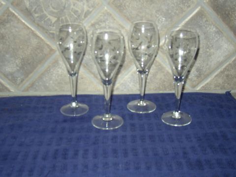 1987 Volkswagen Golf - Four champagne flutes with etched designs are displayed on a blue cloth in front of a tiled wall.