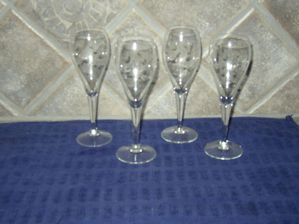 four etched champagne flutes on a blue cloth