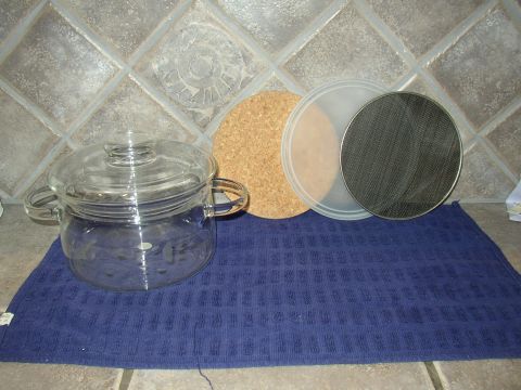 1987 Volkswagen Golf - Glass pot with lid, cork coaster, and metal strainer are displayed on a blue towel.