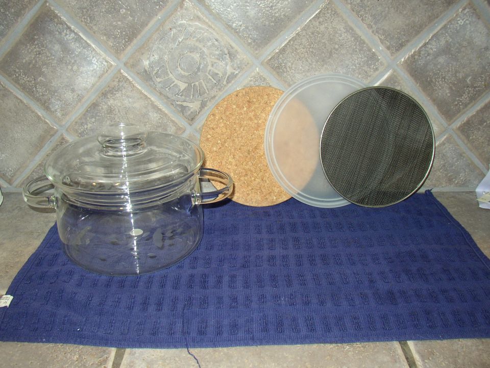 Glass pot, cork coaster, and metal strainer on blue towel