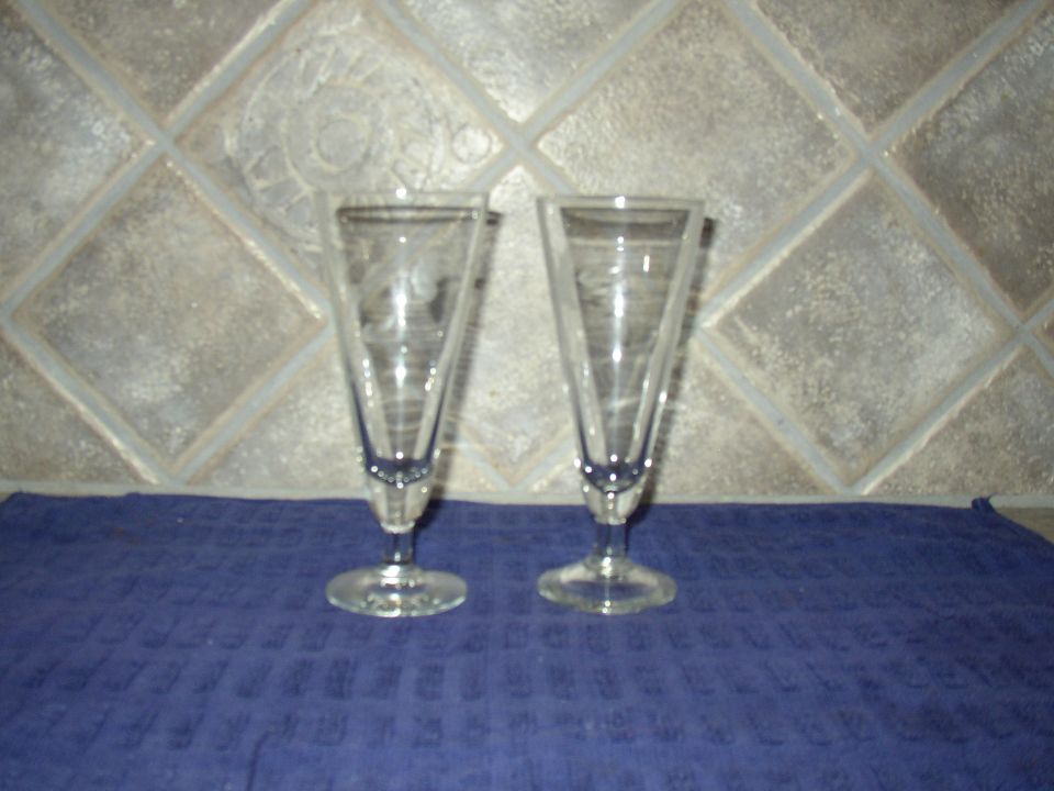 two tall glasses on a blue cloth in front of a tiled wall