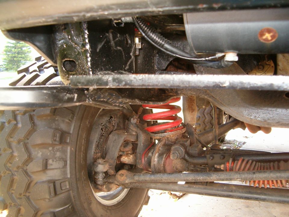 Undercarriage of a vehicle showing suspension, steering components, and a large tire