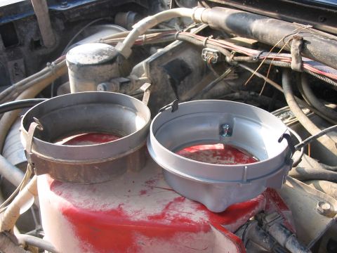 1988 Ford Bronco - Two headlight bezels are shown in an engine bay, one appearing aged and the other new, with a spill of red fluid.