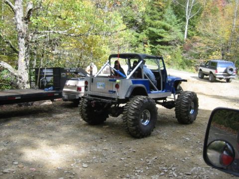 1996 Ford Bronco - A heavily modified Jeep CJ is parked on a dirt road, with another vehicle in the distance.