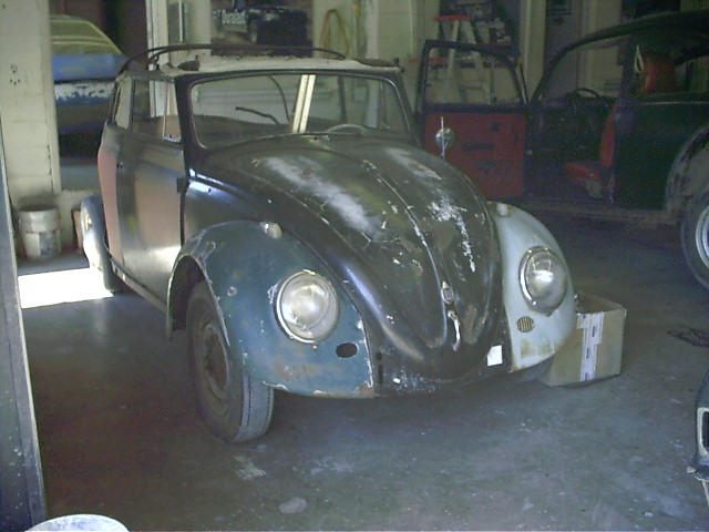 Black VW Beetle convertible project car with mismatched fenders parked in a garage