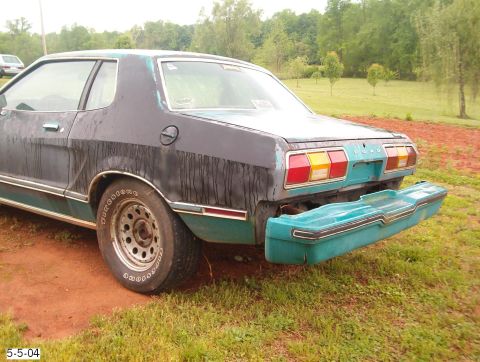 1977 Ford Mustang II - Rear view of a 1977 Ford Mustang II with its bumper detached, parked outdoors.