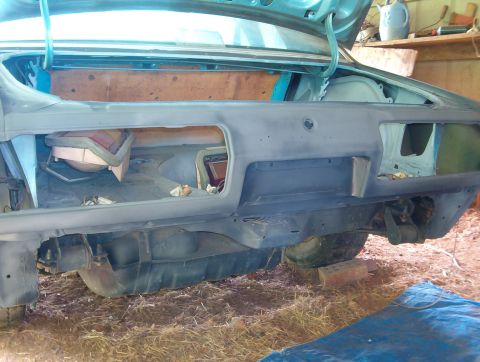 1977 Ford Mustang II - The rear of a car is shown with the trunk open, revealing the interior and bumper area during restoration.