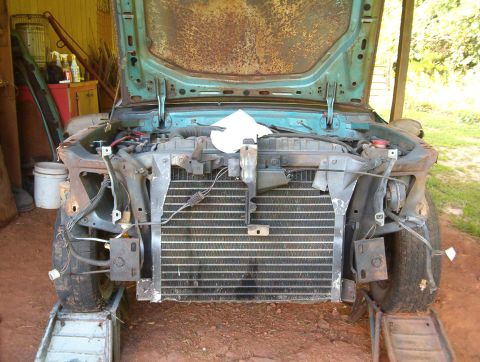 1977 Ford Mustang II - Front end of a car undergoing repairs, with the hood open and radiator visible.