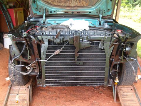 1977 Ford Mustang II - The front end of a vehicle is visible, with the hood open and radiator exposed, indicating ongoing restoration work.