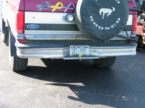 1995 Ford Bronco - The rear of a vehicle, showing the bumper, license plate, and a spare tire cover with a Bronco graphic.