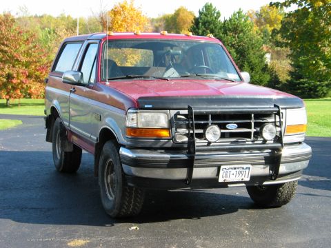 1995 Ford Bronco - This 1995 Ford Bronco is parked outside on a paved surface with trees in the background.
