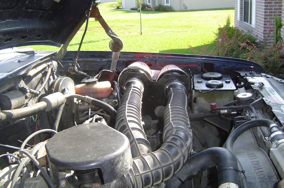Twin ribbed intake tubes and red cone filters in a truck's open engine bay