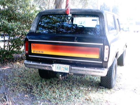 1979 Ford Bronco - Rear view of a black 1978 Ford Bronco with a distinctive orange and yellow stripe across the tailgate.