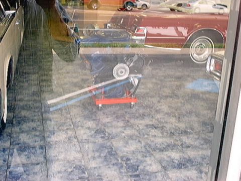 1979 Ford Bronco - Engine on a stand, reflected in a window with other cars.