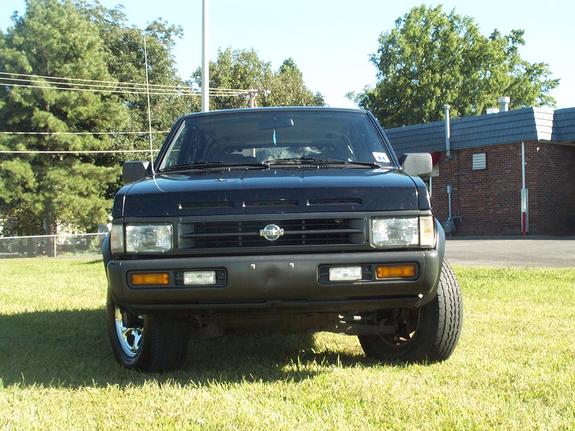 Front view of a black Nissan SUV parked on grass with brick building and trees behind