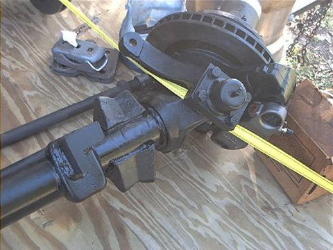1979 Ford Bronco - Close-up of a vehicle's front axle and brake components, laid out on a wooden surface.