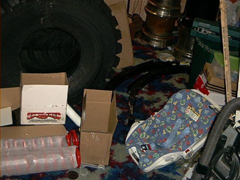 1979 Ford Bronco - A baby car seat and a large tire are among various items stored indoors.