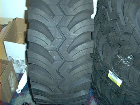 1979 Ford Bronco - A close-up view of a tire's aggressive tread pattern, with boxes in the background.