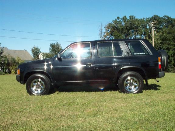 Black Nissan Pathfinder SUV side view with chrome wheels parked on grass