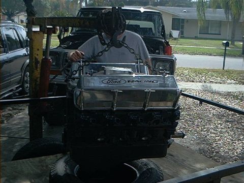 1979 Ford Bronco - Engine being lifted by a chain hoist, with a Ford Racing engine block in focus.