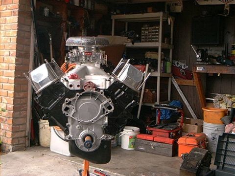 1979 Ford Bronco - Engine assembly displayed on a stand within a cluttered garage environment.
