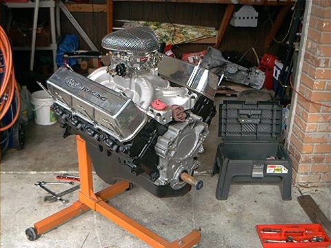 1979 Ford Bronco - Engine with chrome valve covers reading "PRO RACING" is displayed on an orange engine stand in a garage.