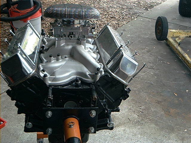 V8 engine with chrome valve covers and air cleaner, mounted on an orange engine stand