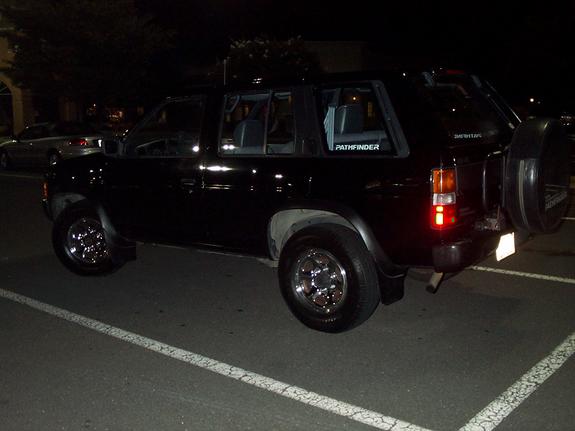 Black Nissan Pathfinder at night, rear three-quarter with rear-mounted spare