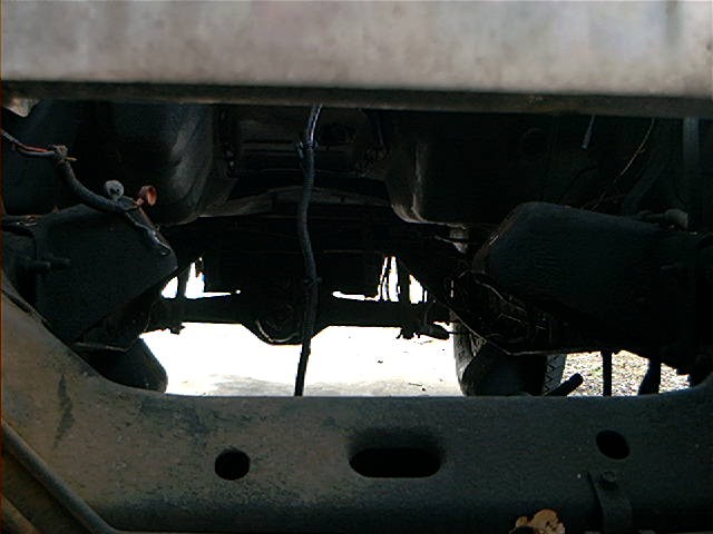 Underside view of vehicle chassis, showing suspension and drivetrain components