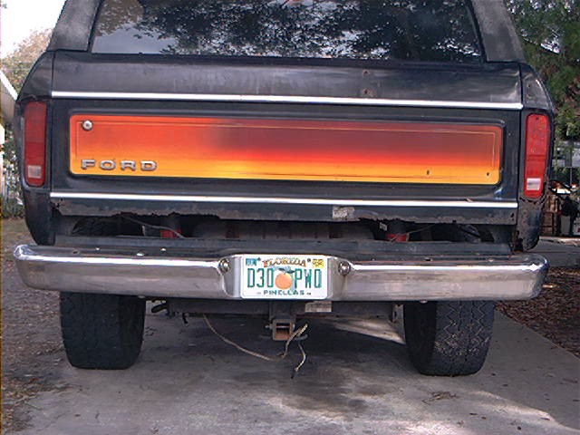 Black 1978 Ford Bronco rear view with orange and red tailgate panel and chrome bumper