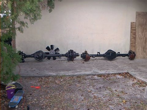 1979 Ford Bronco - Two vehicle axles are displayed outdoors, with one a fan-like component.