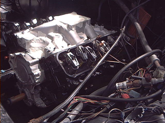 Engine with aluminum intake manifold and exposed valve train, wires and hoses visible