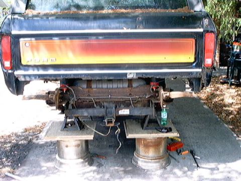 1979 Ford Bronco - The rear of a 1979 Ford pickup truck is shown, with its tailgate a red-to-yellow gradient and the chassis components exposed.