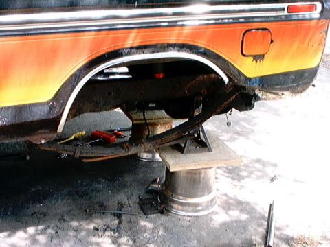 1979 Ford Bronco - Rear suspension work on a 1979 Ford Bronco, showing the removed leaf spring and wheel well.
