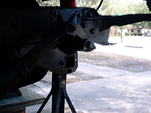 1979 Ford Bronco - The underside of a vehicle's frame, showing a hitch receiver, is elevated on jack stands.