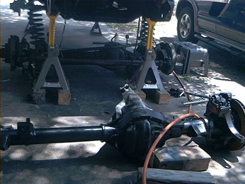 1979 Ford Bronco - Vehicle undergoing maintenance, with drivetrain components exposed and supported by jack stands.