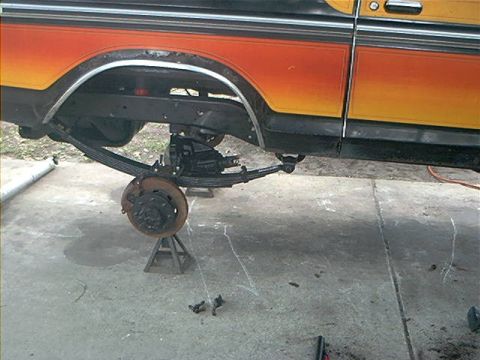 1979 Ford Bronco - The rear suspension of a 1979 Ford Bronco is shown while on jack stands, with the leaf springs and brake assembly visible.