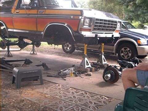 1979 Ford Bronco - Ford Bronco is up on jack stands for repairs, with parts and tools scattered around.