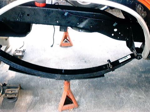 1979 Ford Bronco - Close-up of a vehicle's leaf spring assembly supported by jack stands, with a part number visible on the spring.