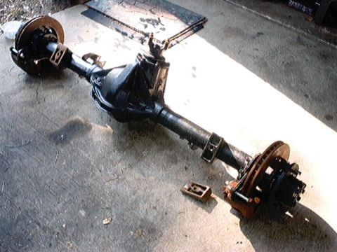 1979 Ford Bronco - A disassembled rear axle assembly, likely from a Ford Bronco, rests on a concrete surface.