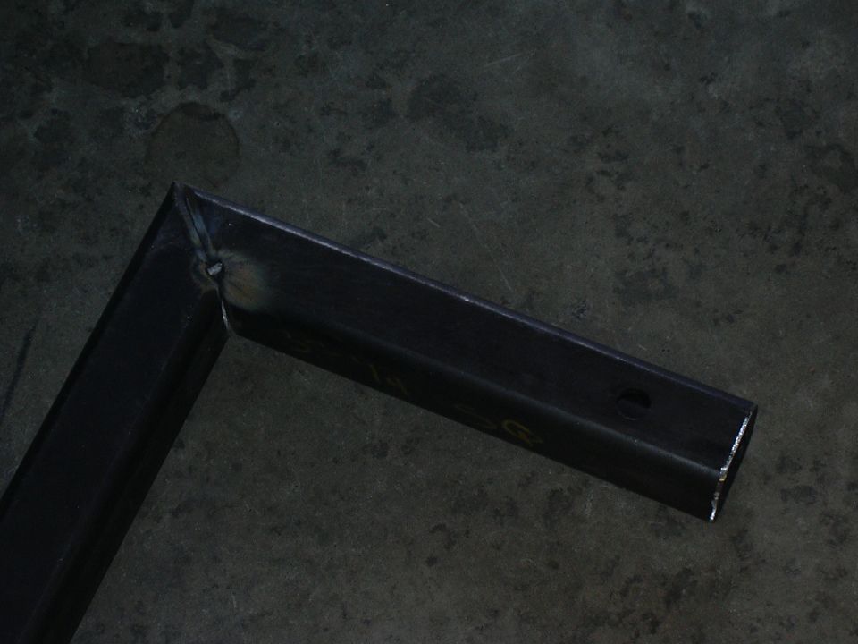 Welded square steel tubing corner joint lying on a concrete floor