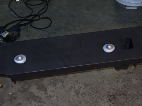 1991 Ford Bronco - Black metal bumper part with two circular silver reflectors and a square cutout is on the floor.