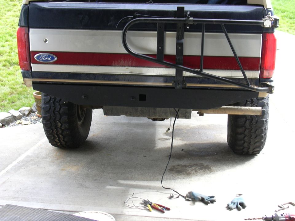 Rear of lifted Ford truck on mud tires with tube swing-out tire carrier over tailgate