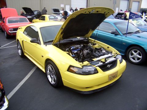 1978 Ford Mustang II - A bright yellow Ford Mustang from the early 2000s is displayed with its hood open at a car show.