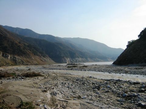 1985 Ford Bronco - A wide, rocky riverbed stretches towards distant mountains under a clear sky.