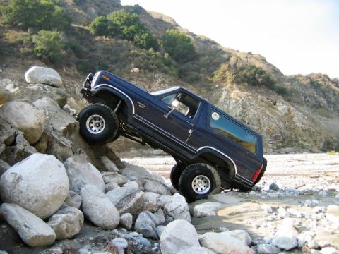 1985 Ford Bronco - 1985 Ford Bronco navigating a rocky trail in a , natural landscape.