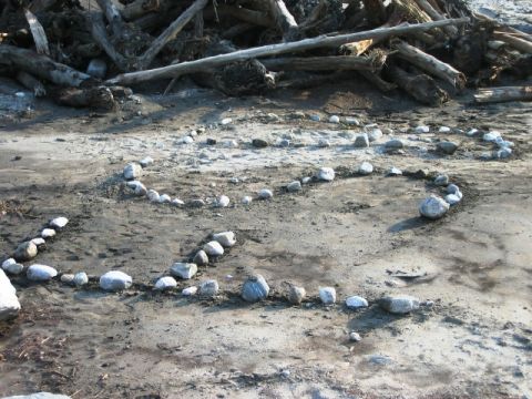 1985 Ford Bronco - Heart shape made of rocks on a sandy surface, with driftwood piled behind.