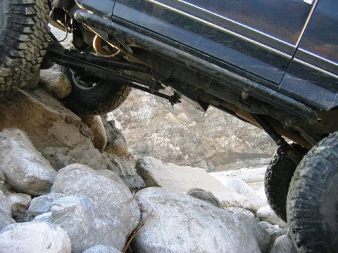 1985 Ford Bronco - The vehicle's suspension and tires are tested as it climbs over large rocks on a trail.